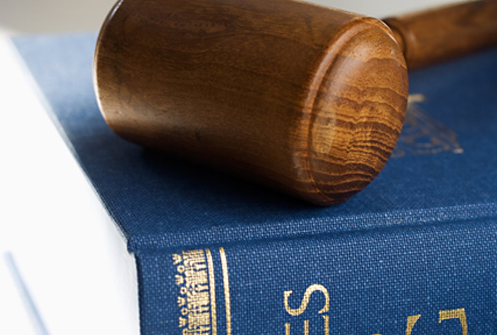 Träklubba ligger ovanpå en lagbok med texten Sveriges Rikes Lag.