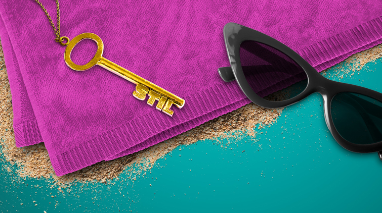 En guldnyckel och ett par svarta solglasögon på en rosa handduk.